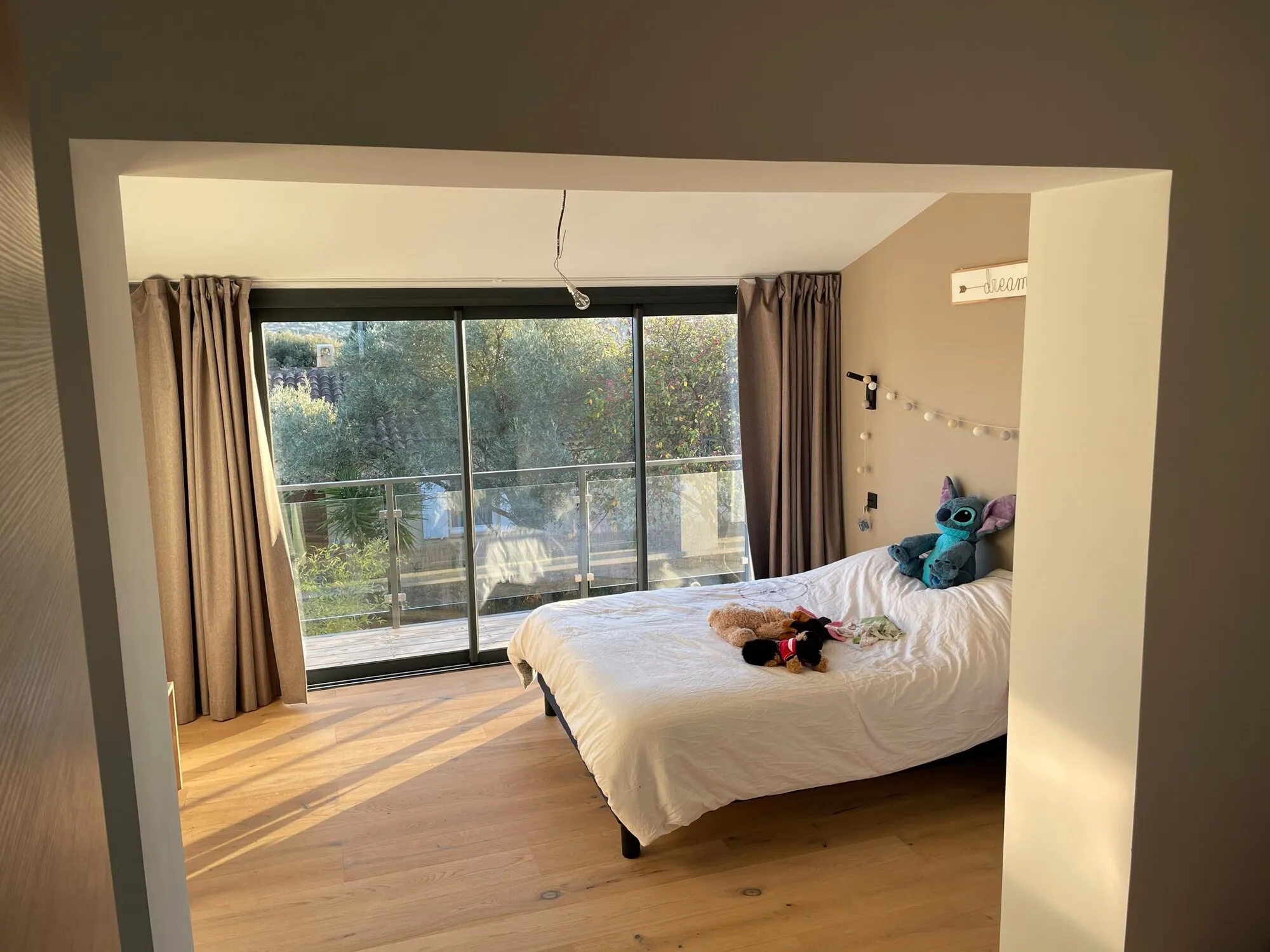 Chambre avec grande baie vitrée ouverte sur le jardin