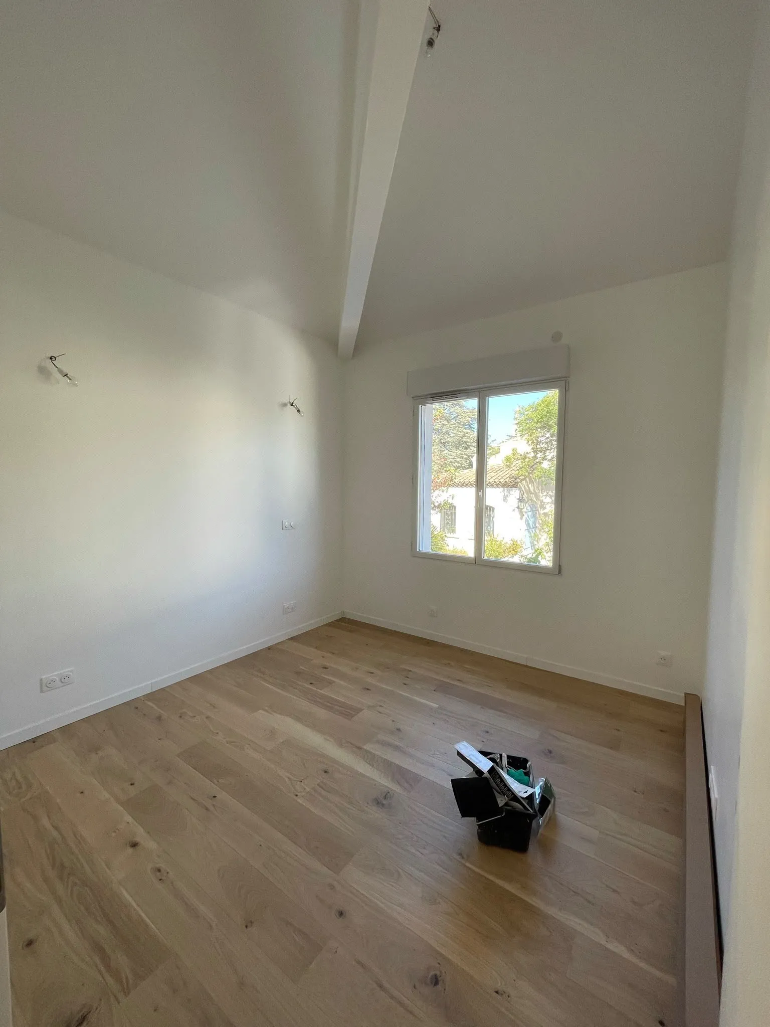 Chambre aux murs et plafonds fraîchement repeints, parquet en chêne