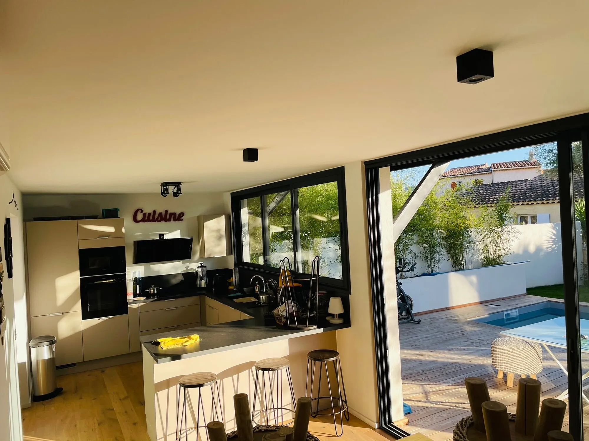 Cuisine ouverte rénovée avec îlot et baies vitrées sur la piscine