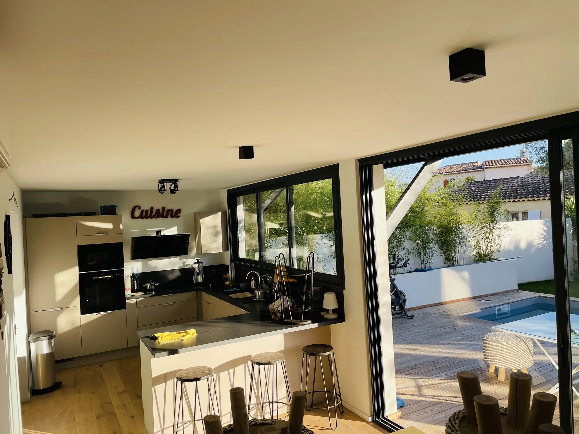 Cuisine ouverte rénovée avec grandes baies vitrées sur la terrasse