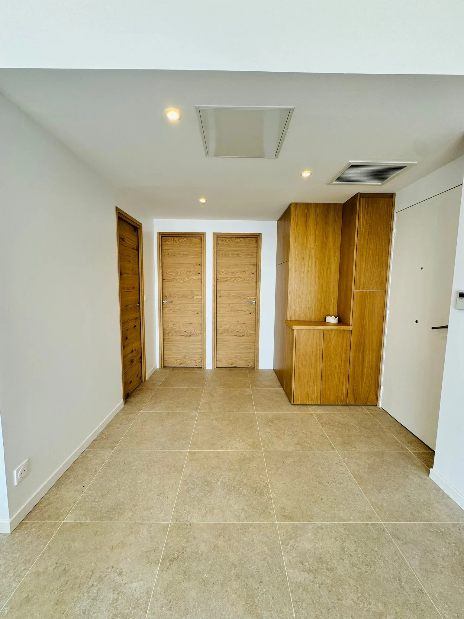 Entrée rénovée en carrelage grand format beige et portes en chêne