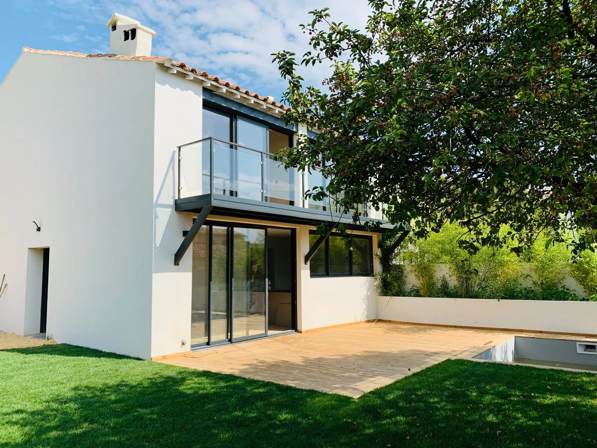 Façade rénovée en blanc avec baies vitrées et balcon en verre