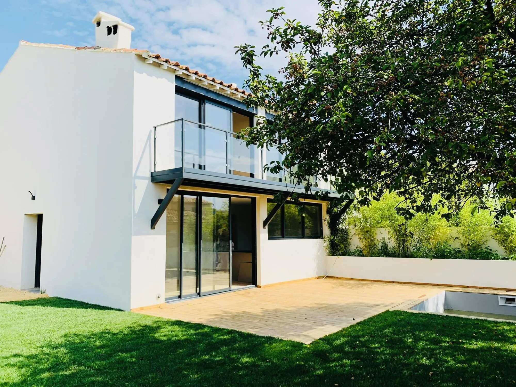 Maison rénovée avec façade blanche et grandes baies vitrées