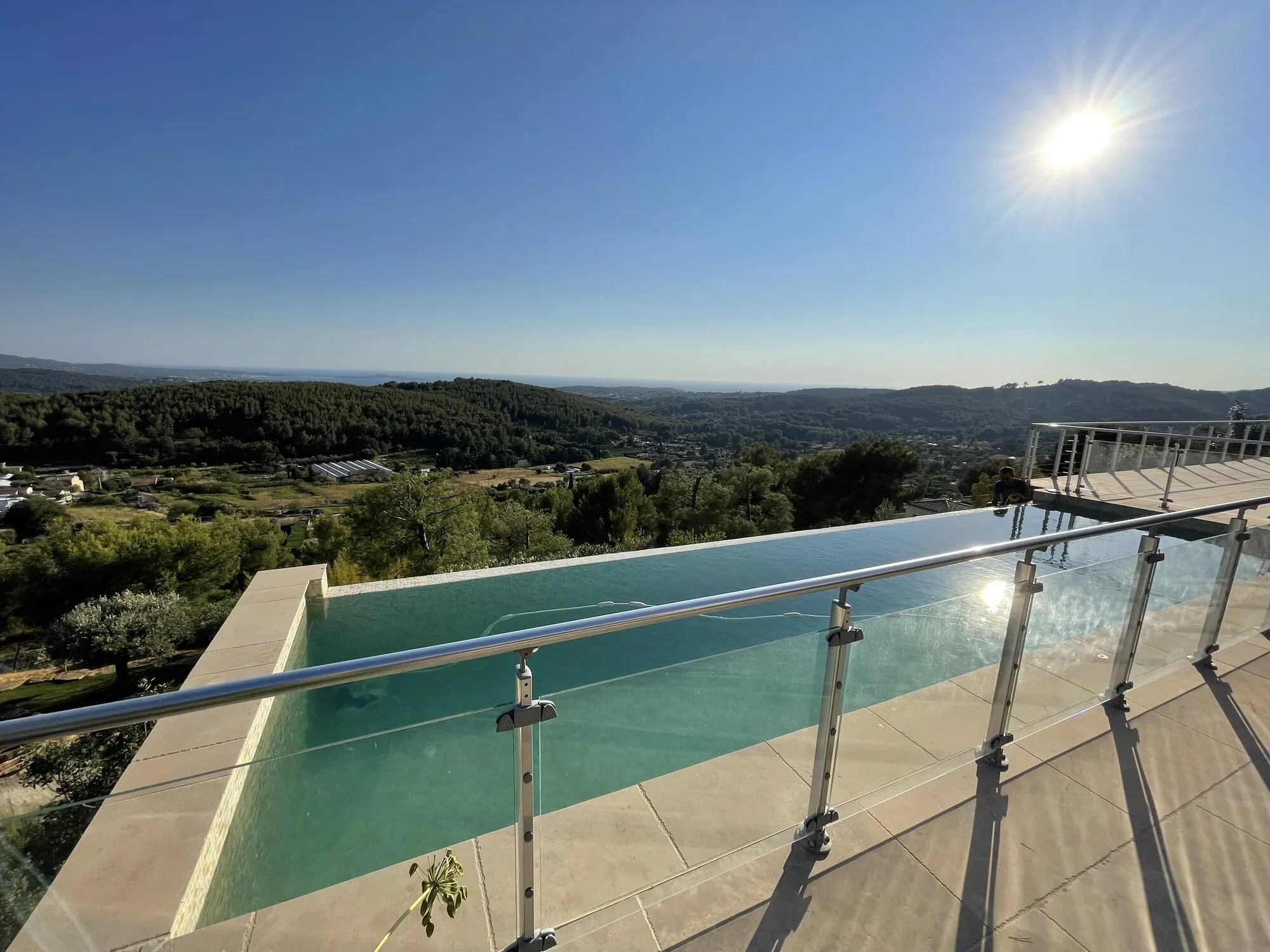 Piscine à débordement avec garde-corps vitré face aux collines