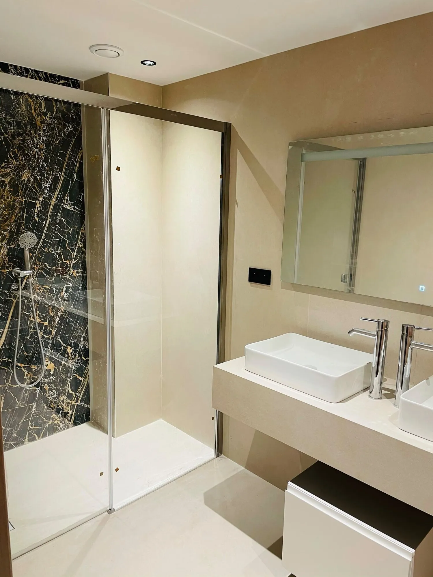 Salle de bains avec douche en marbre noir et vasque posée