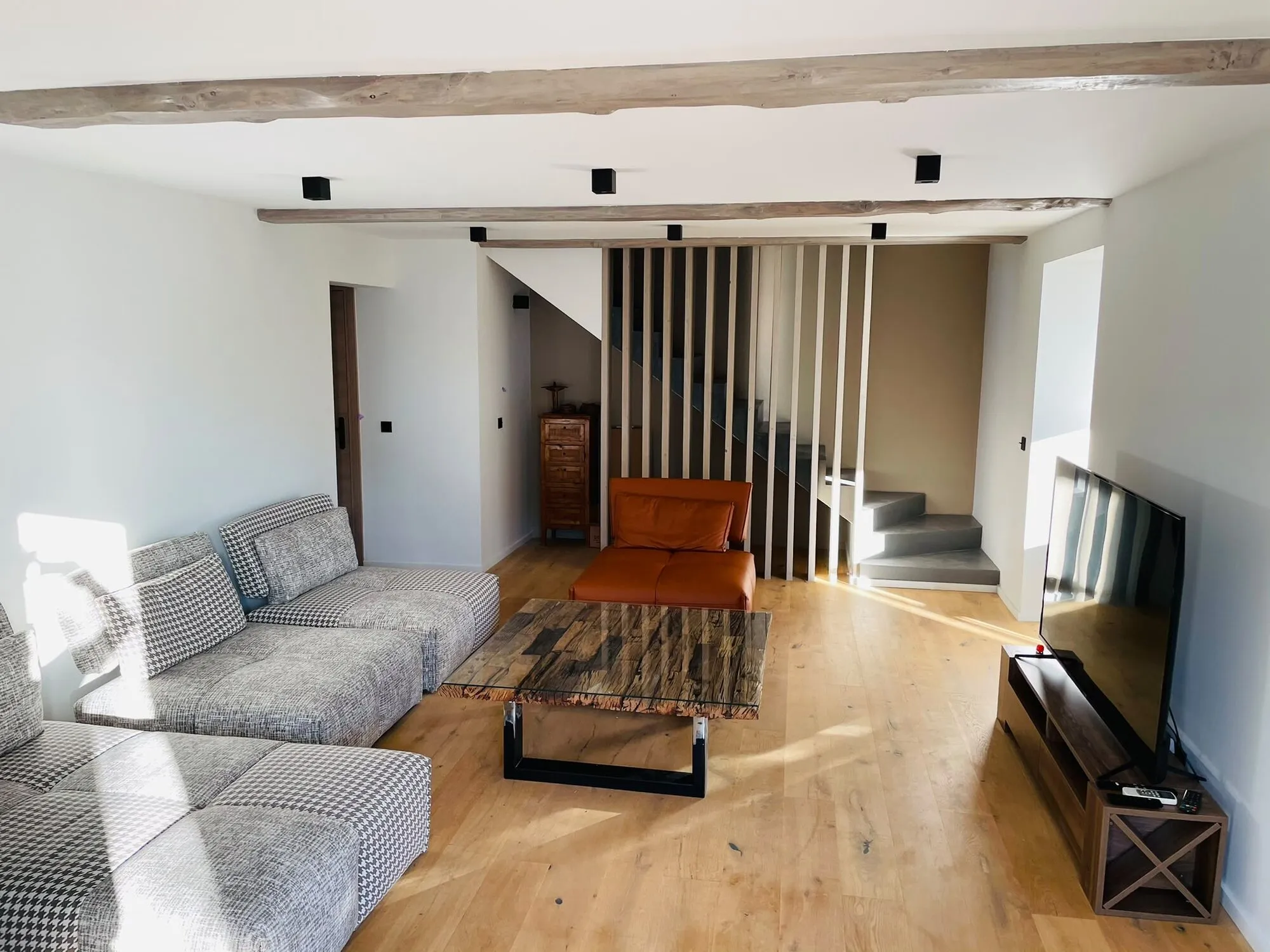 Salon rénové avec parquet chêne, poutres apparentes et escalier claustra