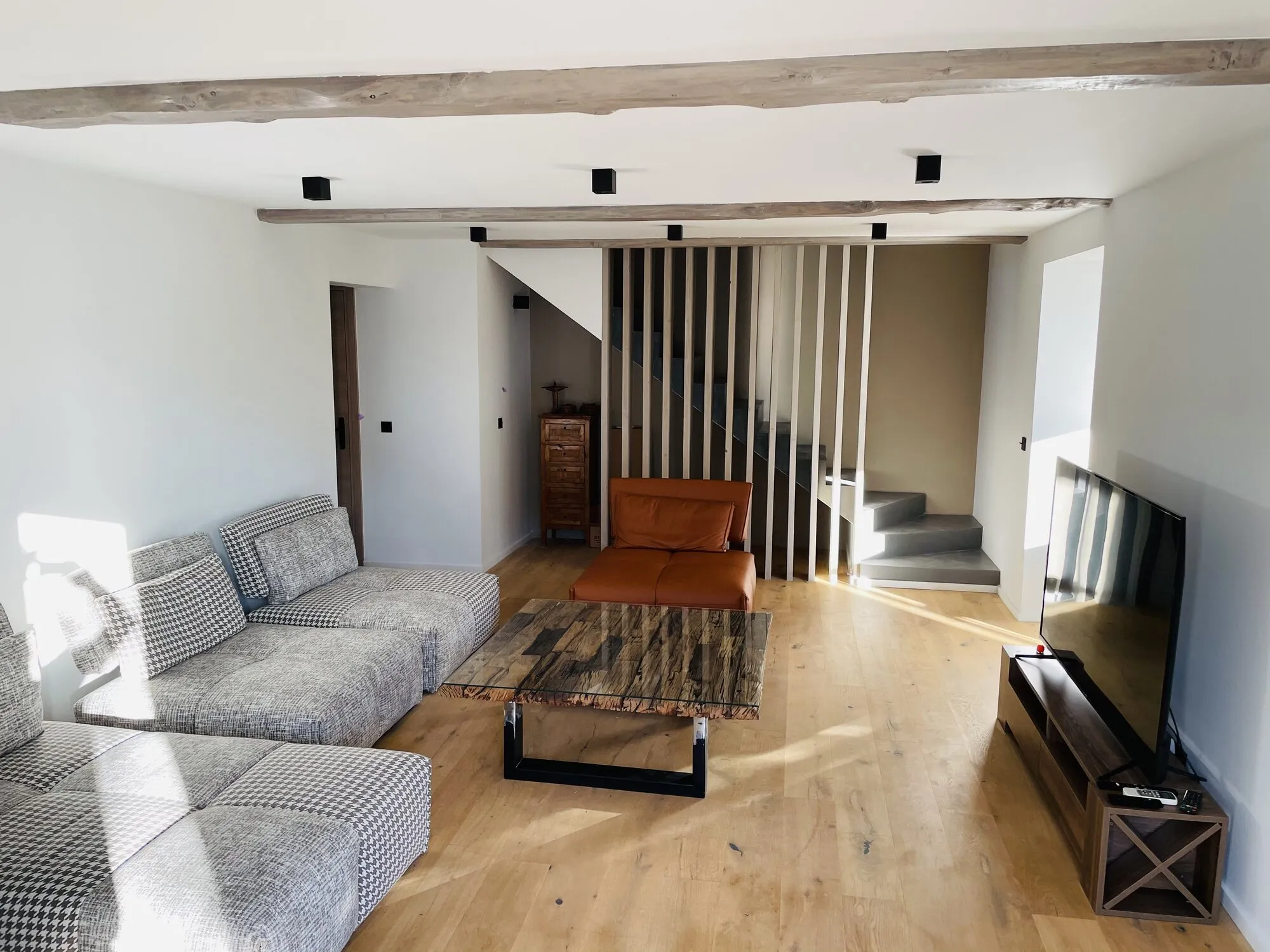 Salon rénové avec parquet en chêne, poutres et escalier